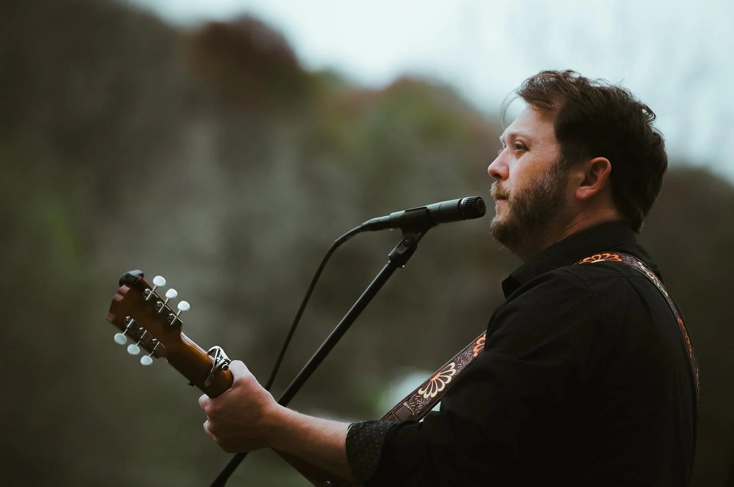 David Sparrow performing outdoors with an acoustic guitar