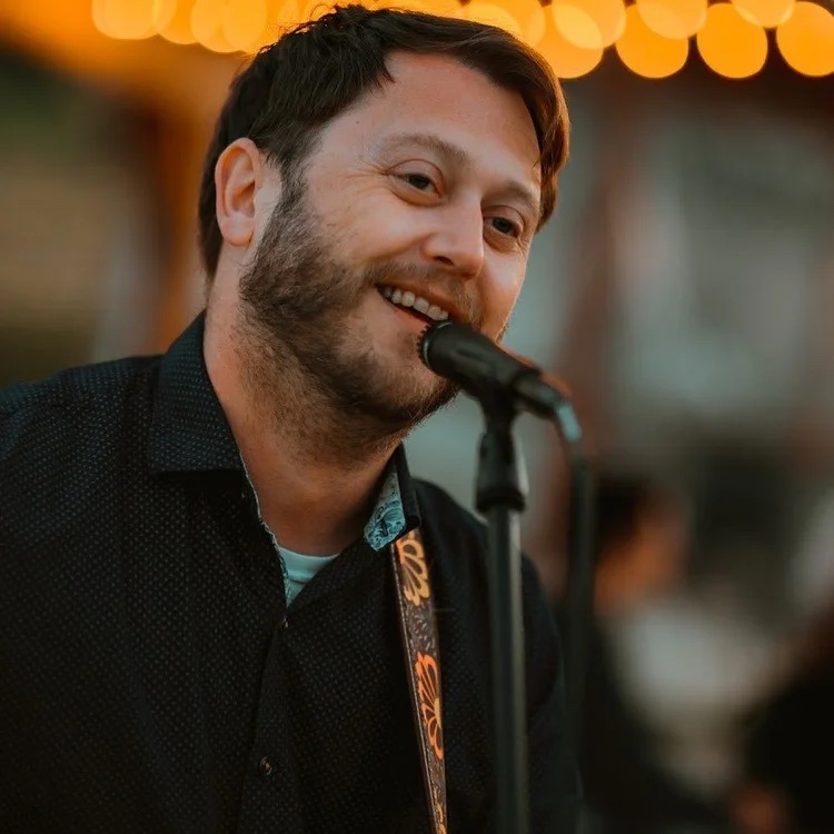 David Sparrow smiling while performing at a microphone