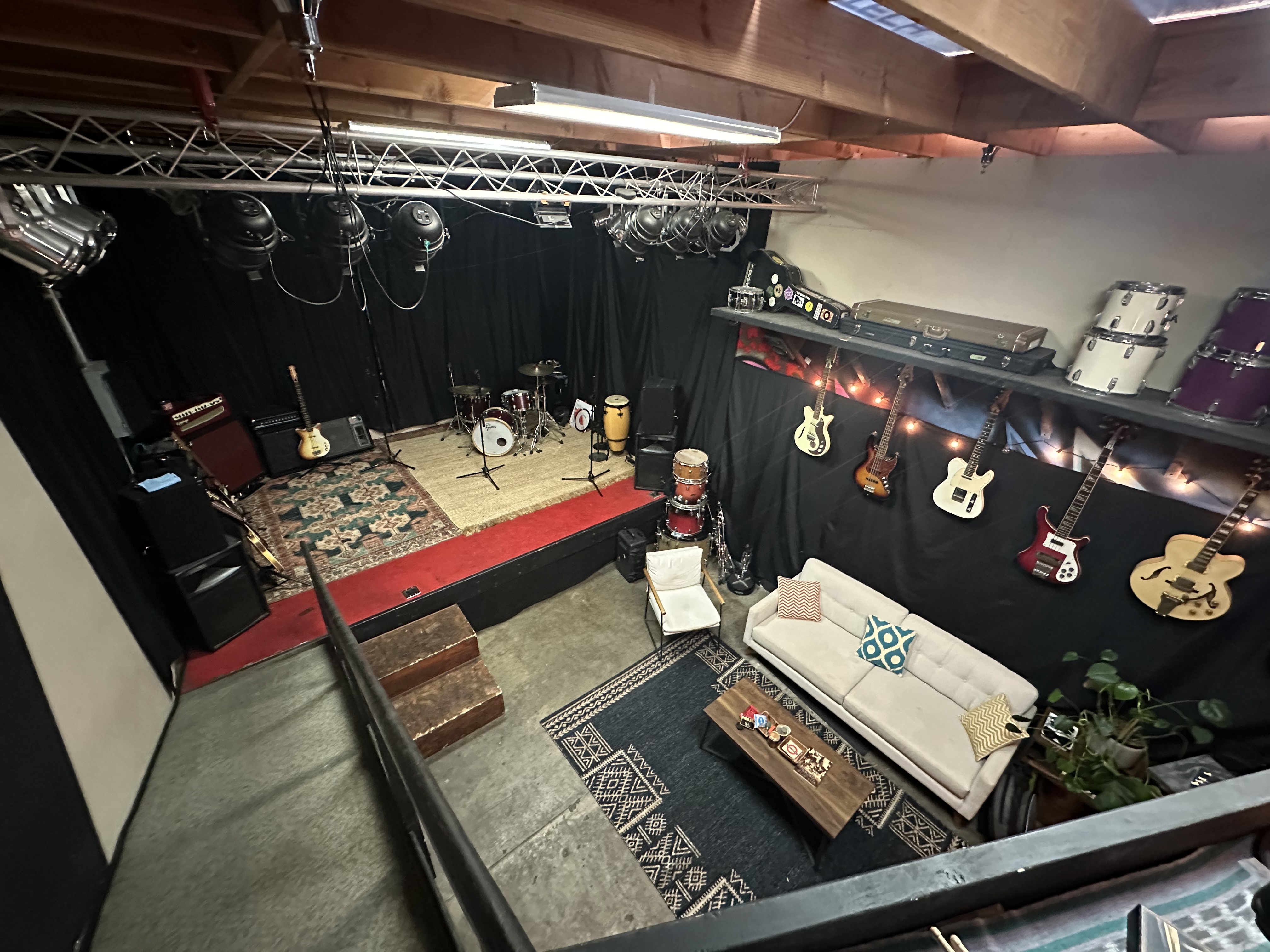 Motel Media stage and sofa lounge viewed from the mezzanine, with instruments along the wall